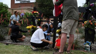 Personas colocando ofrendas florales frente al centro comercial Allen Premium Outlets de Texas