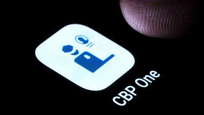 Captura del icono de la app CBP One en una pantalla con un dedo haciendo clic