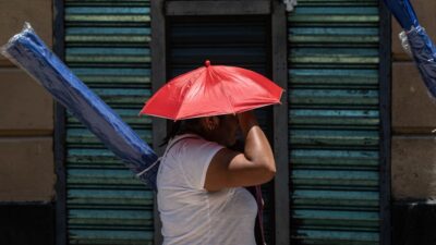 Mujer se protege del sol en la calle con una sombrilla