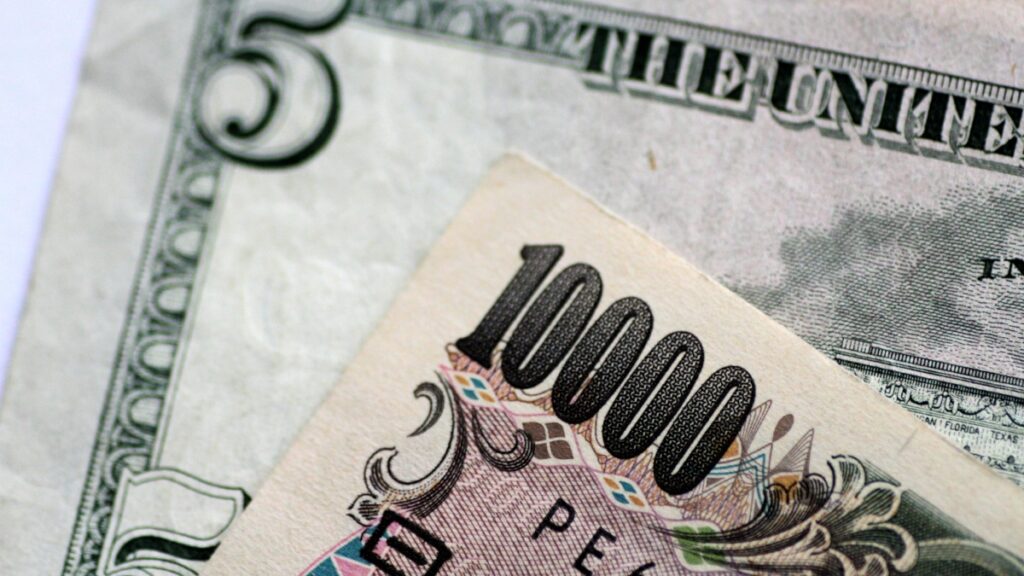 Dólar hoy: Fotografía de un billete de cinco dólares bajo uno de 10 mil yenes