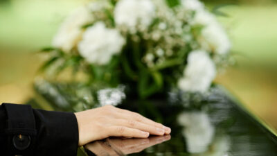 Persona con su mano sobre un féretro en un funeral