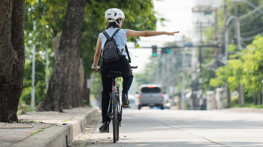 Señales ciclistas: Ciclista circulando sobre una calle marcando cambio de carril