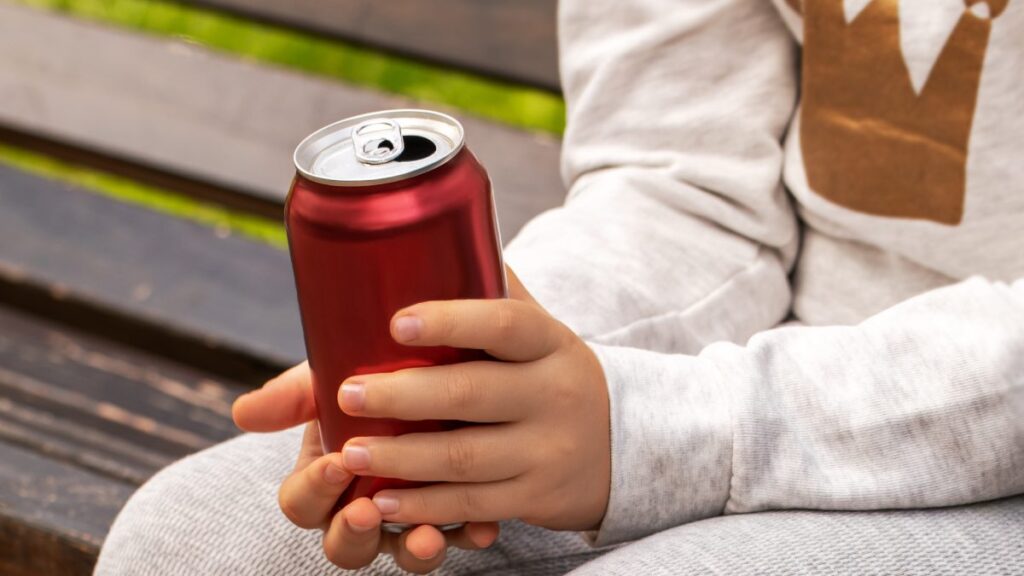 Niño sosteniendo una bebida energética en lata roja