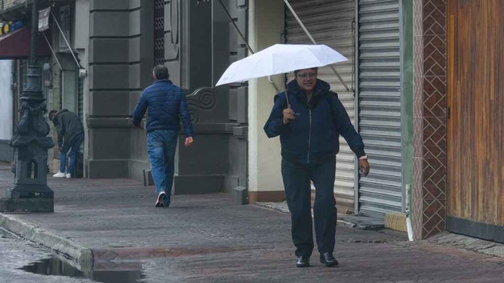 Mujer caminando con paraguas en una calle del Centro Histórico de la CDMX
