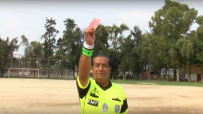 Árbitro de futbol amateur sacando la tarjeta roja