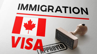 Canadá empleo: Bandera de Canadá bajo la palabra "migración" en inglés y el sello de aprobado