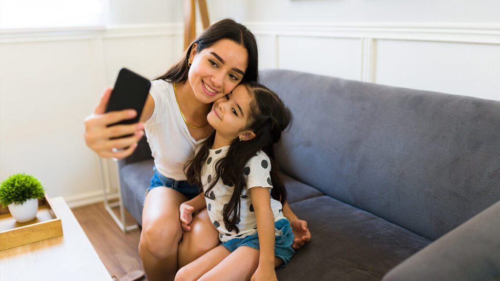 Sharenting: Fotografía de mamá con su hija tomándose una selfie en el sillón