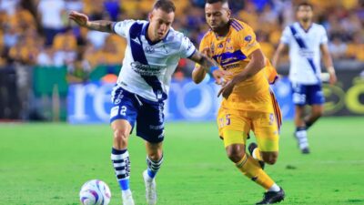 Jugadores de Tigres y Puebla disputan el balón en partido de futbol