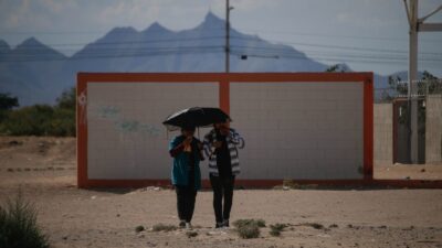 Personas caminan bajo un paraguas en un camino desértico