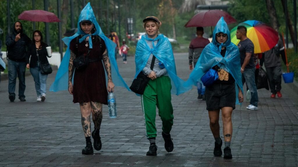 Jóvenes se cubren de la lluvia con plásticos azules en un corredor de la CDMX