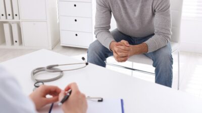 Hombre sentado en una silla frente a un doctor en una cita médica