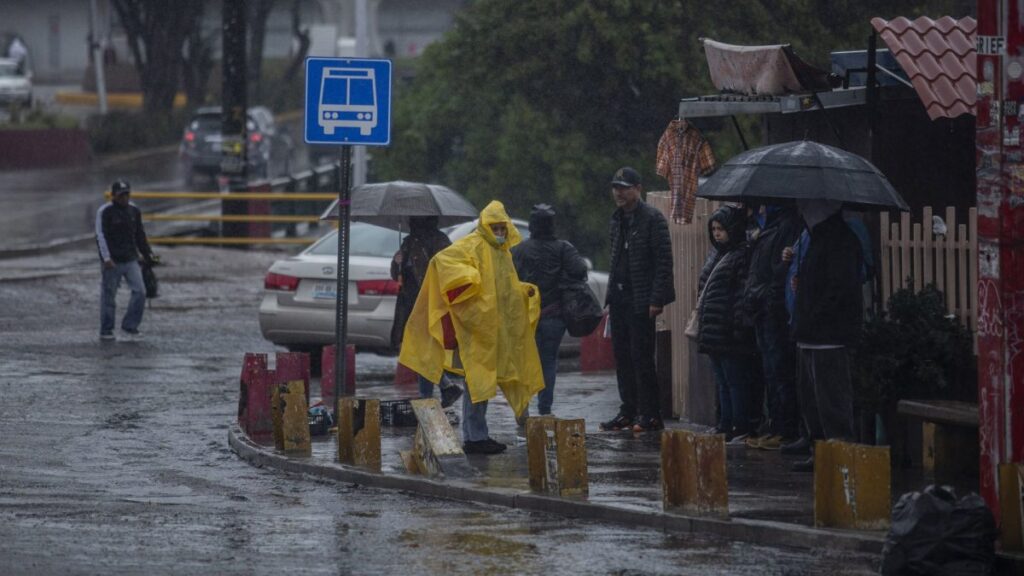 Personas se cubren de la lluvia con paraguas e impermeables en una calle de México