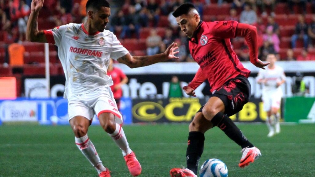 Jugadores de Xolos de Tijuana y Toluca disputan el balón en partido de la Liga MX