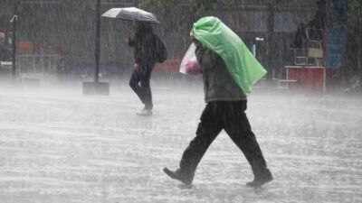 Hombre camina bao una fuerte lluvia cubriéndose con un plástico verde