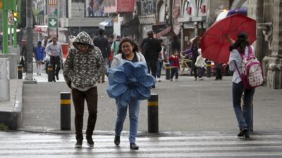 Personas caminando por la CDMX, una de ellas con paraguas