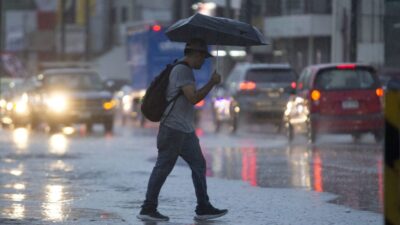 Joven con mochila y paraguas camina bajo fuerte lluvia en Nuevo León