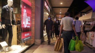 Personas caminan por el pasillo de un centro comercial con compras en las manos