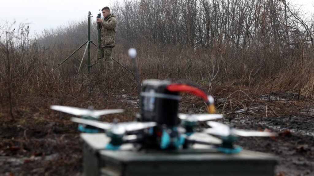 Dron en primer plano y operador militar de drones al fondo en un bosque