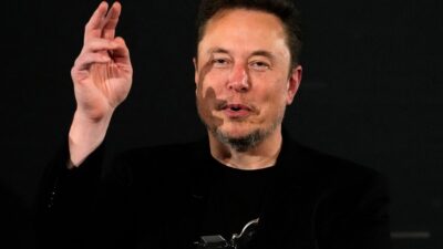 Elon Musk alzando la mano, vestido de negro