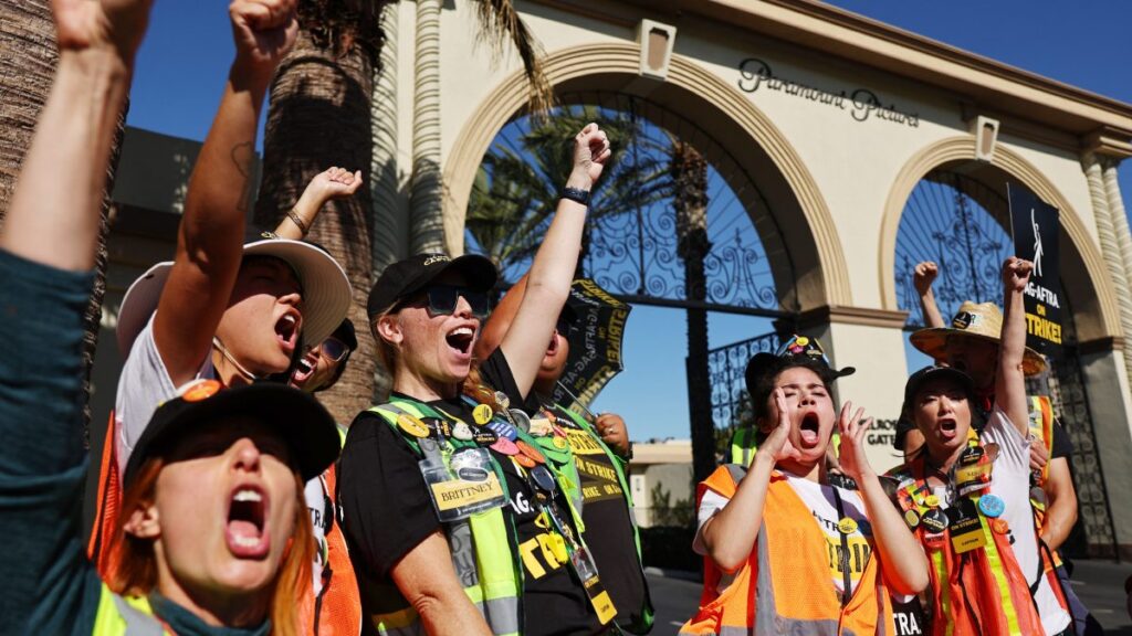 Trabajadores de Hollywood en huelga se manifiestan afuera de un estudio con los brazos en alto