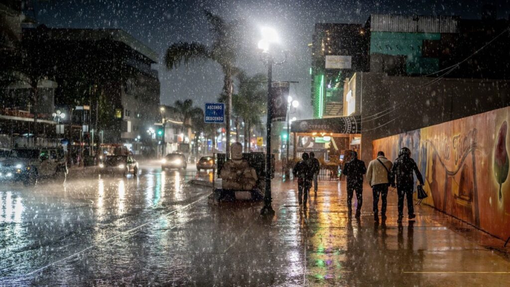 Gente caminando de noche bajo la lluvia
