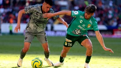 Jugadores del Atlas y León disputan el balón en partido de futbol de la Liga MX