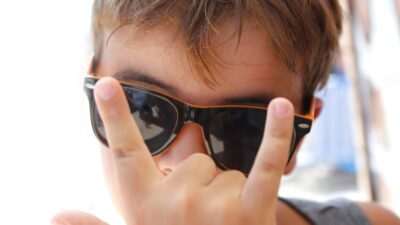 Niño con lentes haciendo la señal de cuernos con su mano