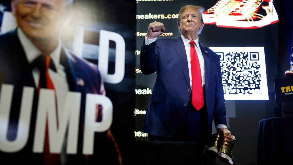Donald Trump con unos tenis dorados en su mano, durante un evento de campaña