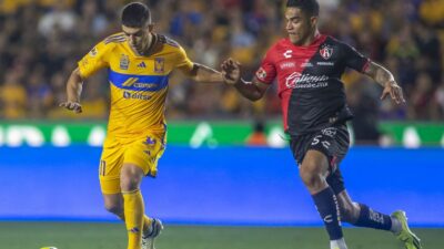 Jugadores de Tigres y Atlas disputan el balón en partido de la Liga MX