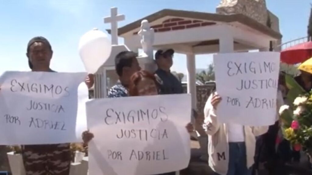 Personas se manifiestan en un panteón con cartulinas con la leyenda "Justicia para Adriel"