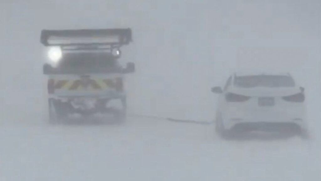 Autos avanzan bajo una densa neblina y nieve provocada por una tormenta invernal