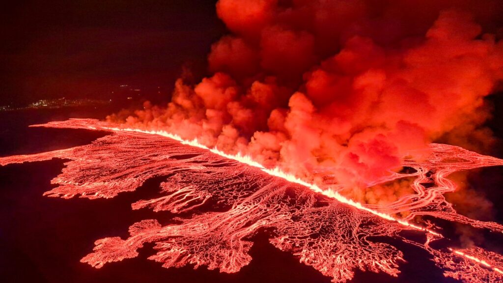 Lava volcánica y humo iluminan el cielo de color naranja