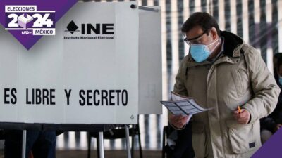 Hombre con boleta electoral en casilla del INE para votación