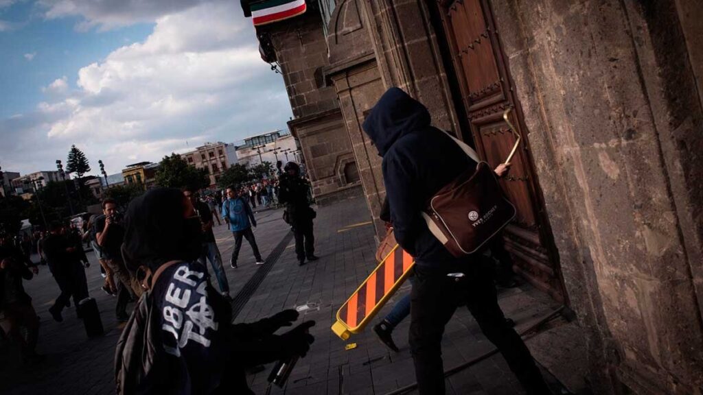 Normalistas de Ayotzinapa derriban puerta de Palacio Nacional e intentan entrar