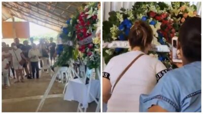 Funeral con coronas de flores y mujer tomando fotos con su celular
