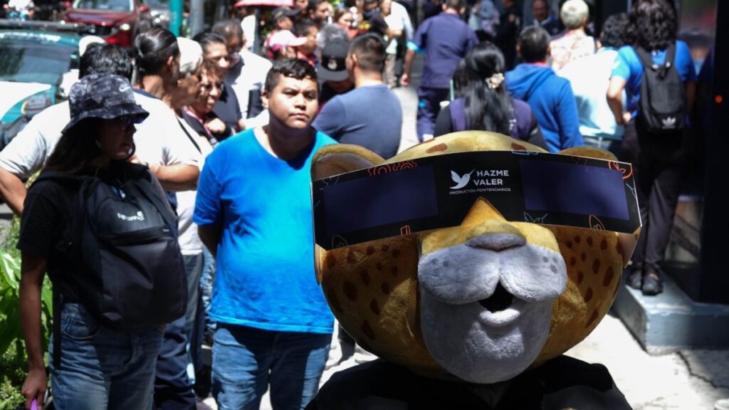 Botarga con lentes especiales para ver el eclipse. Atrás de él decenas de personas formadas.