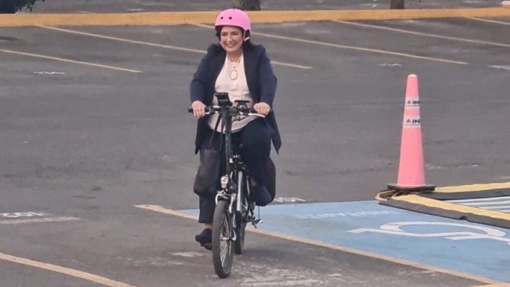Xóchitl Gálvez llegando al INE en bicicleta portando un casco rosa