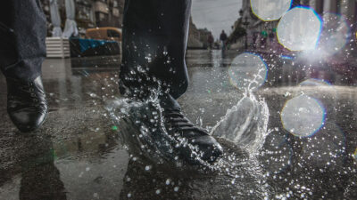 Hombre pisando un charco después de que la lluvia dejó espuma en las calles
