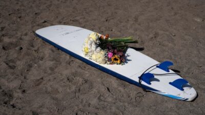 Arreglo floral sobre una tabla de surf durante un homenaje a los surfistas extranjeros en una playa de Ensenada