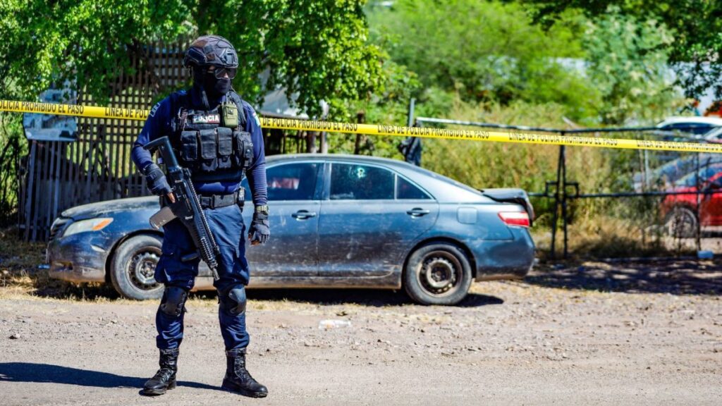 Policía vigila carro en escena del crimen en Culiacán, Sinaloa